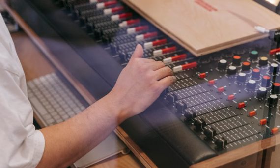 Close-up of an audio engineer's hand adjusting a mixing console in a recording studio.